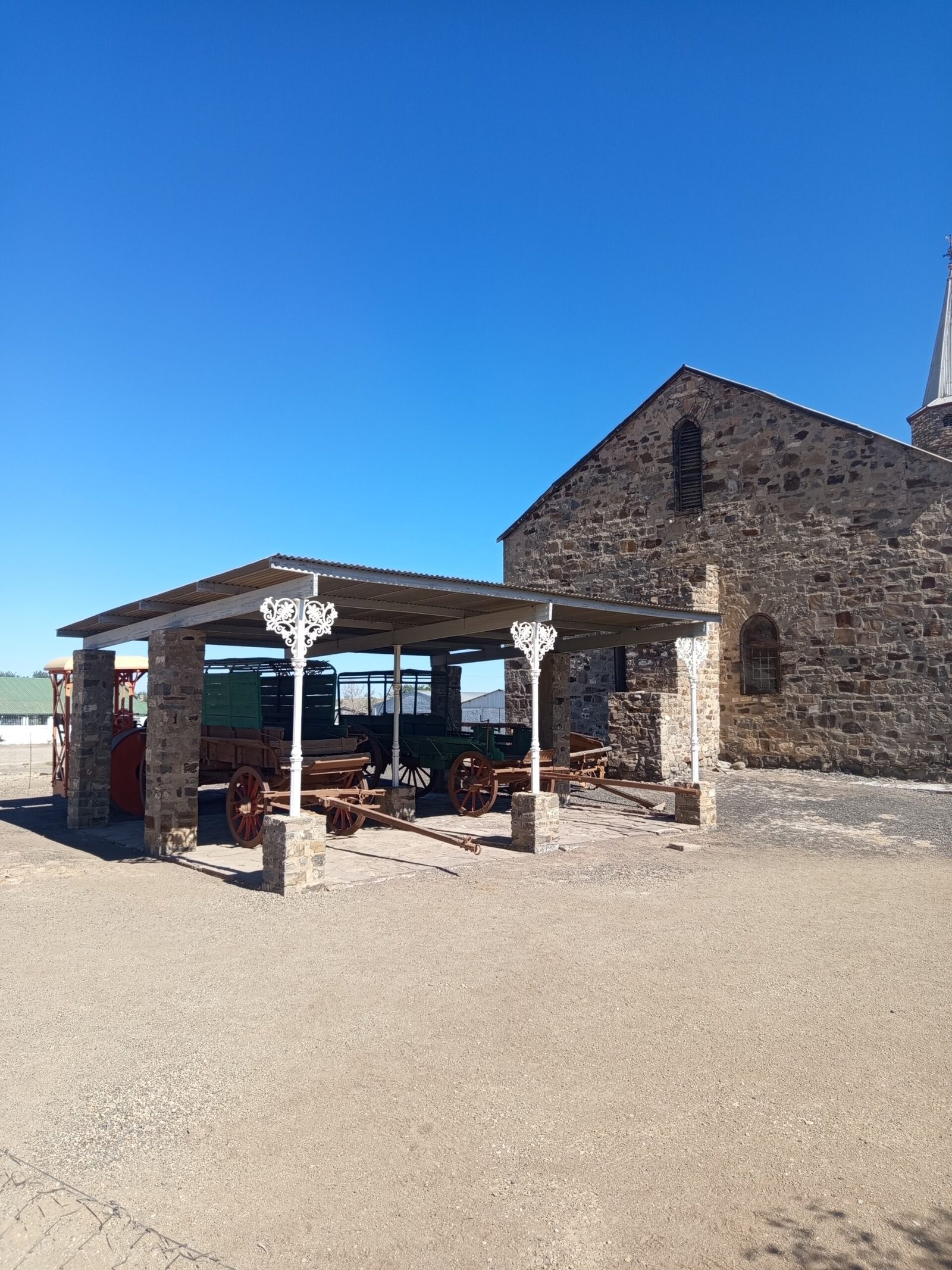 Old horse or ox wagons under a protective roof next to the church
